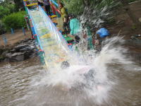 写真。水しぶきをあげてウォータースライダーをすべる子ども。