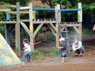 （写真）ホースから出た水しぶきで遊ぶ親子